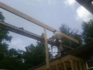 Carpenter setting a ridge beam over a new addition frame — Ice Dam Removal by Roofing Brothers in Malone