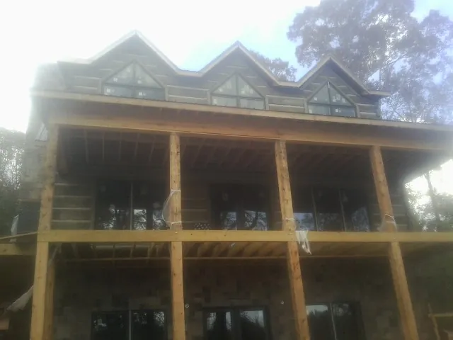Dormers and porch framing on a large log home under construction — Roof Coating work by our crew in Malone